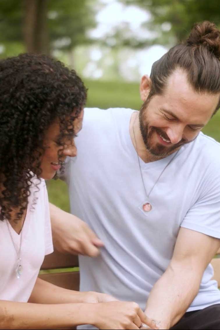 Couple holding a The Liquid Crystal Necklace to their wrist in the park